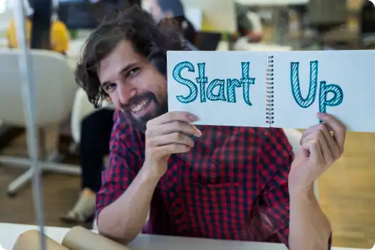 Mitarbeiter mit einem Start Up Schild. Steht für offene neue Strukturen und kurze Prozesse