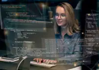Bild zeigt eine Mitarbeiterin am PC. Sie schreibt code welcher direkt im Vordergrund eingeblendet wird